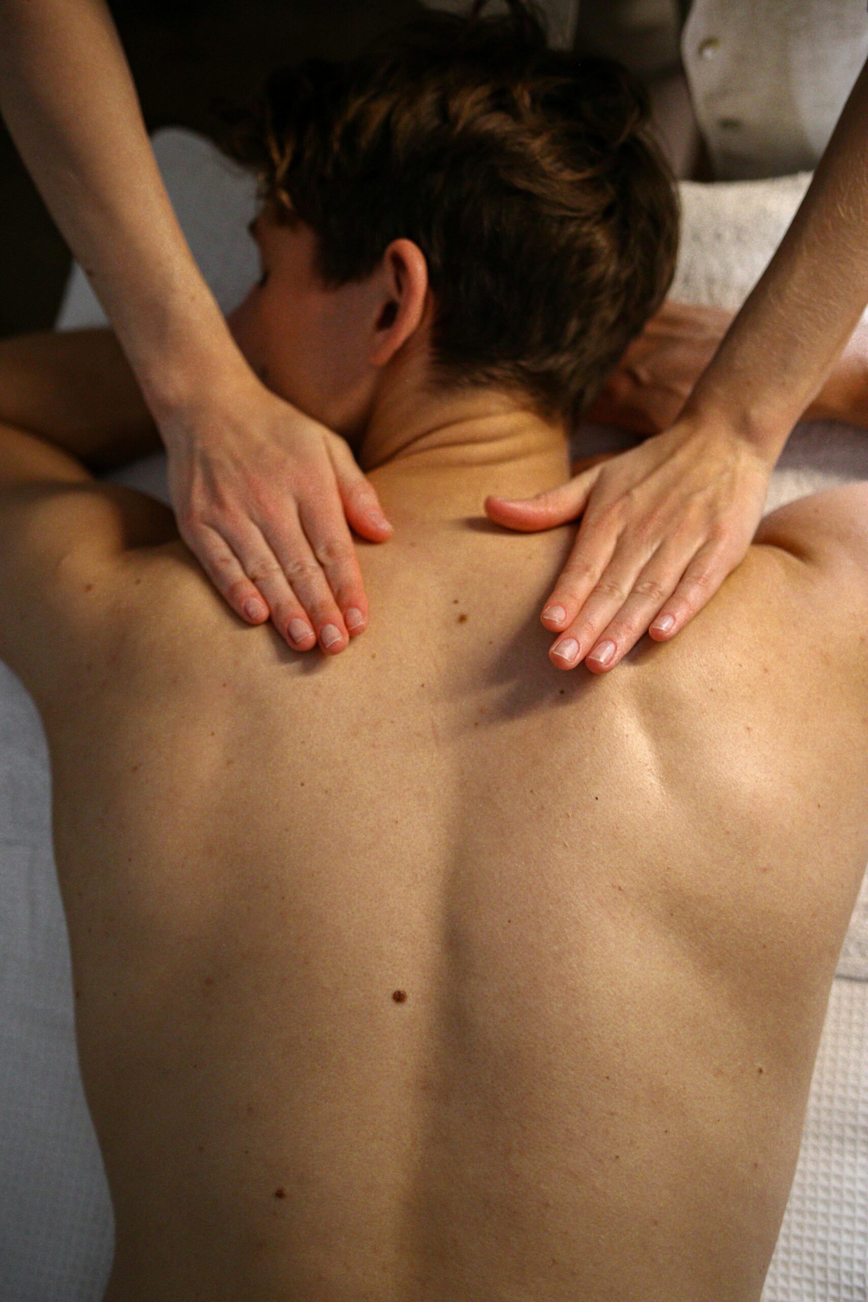 Man receiving relaxing massage therapy on upper back at spa.