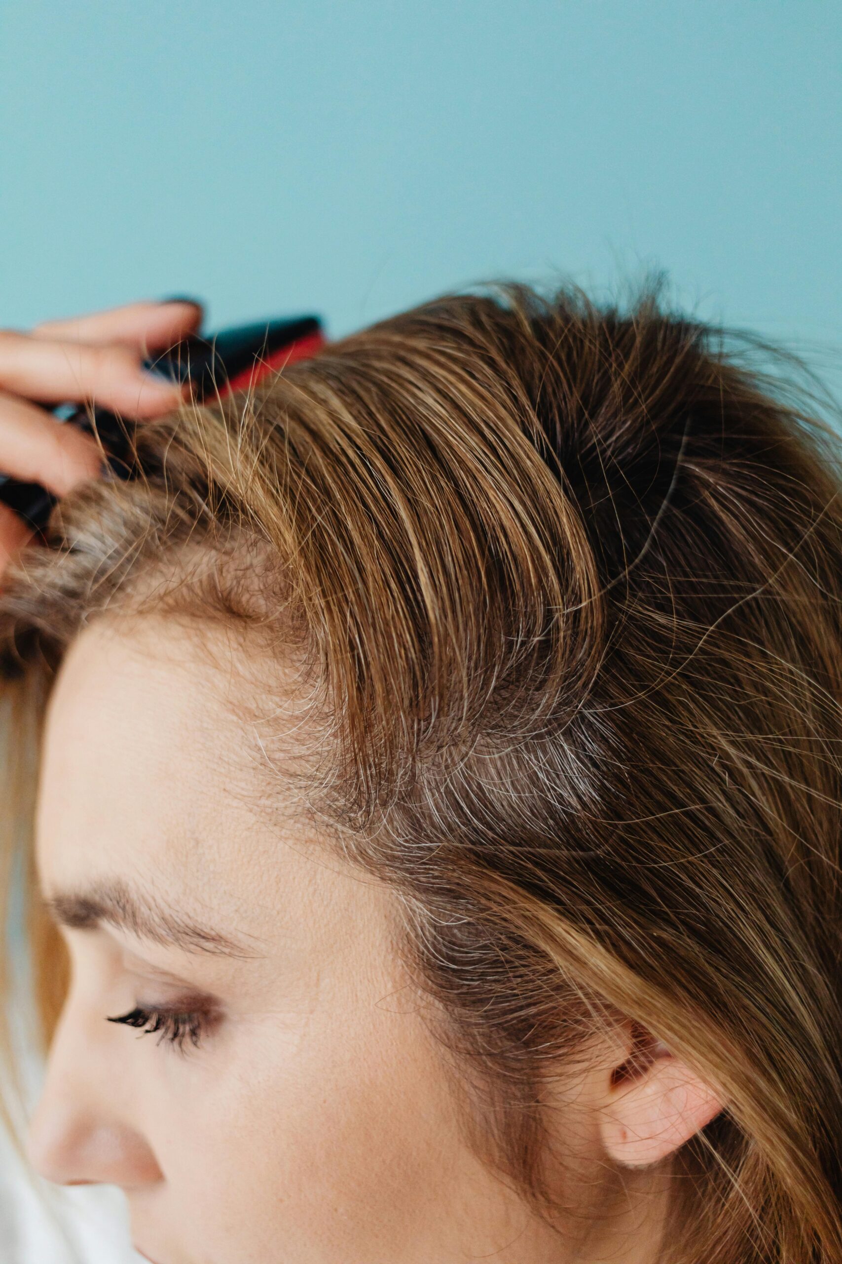 Close-up of a woman brushing her hair against a blue background in a studio setting.